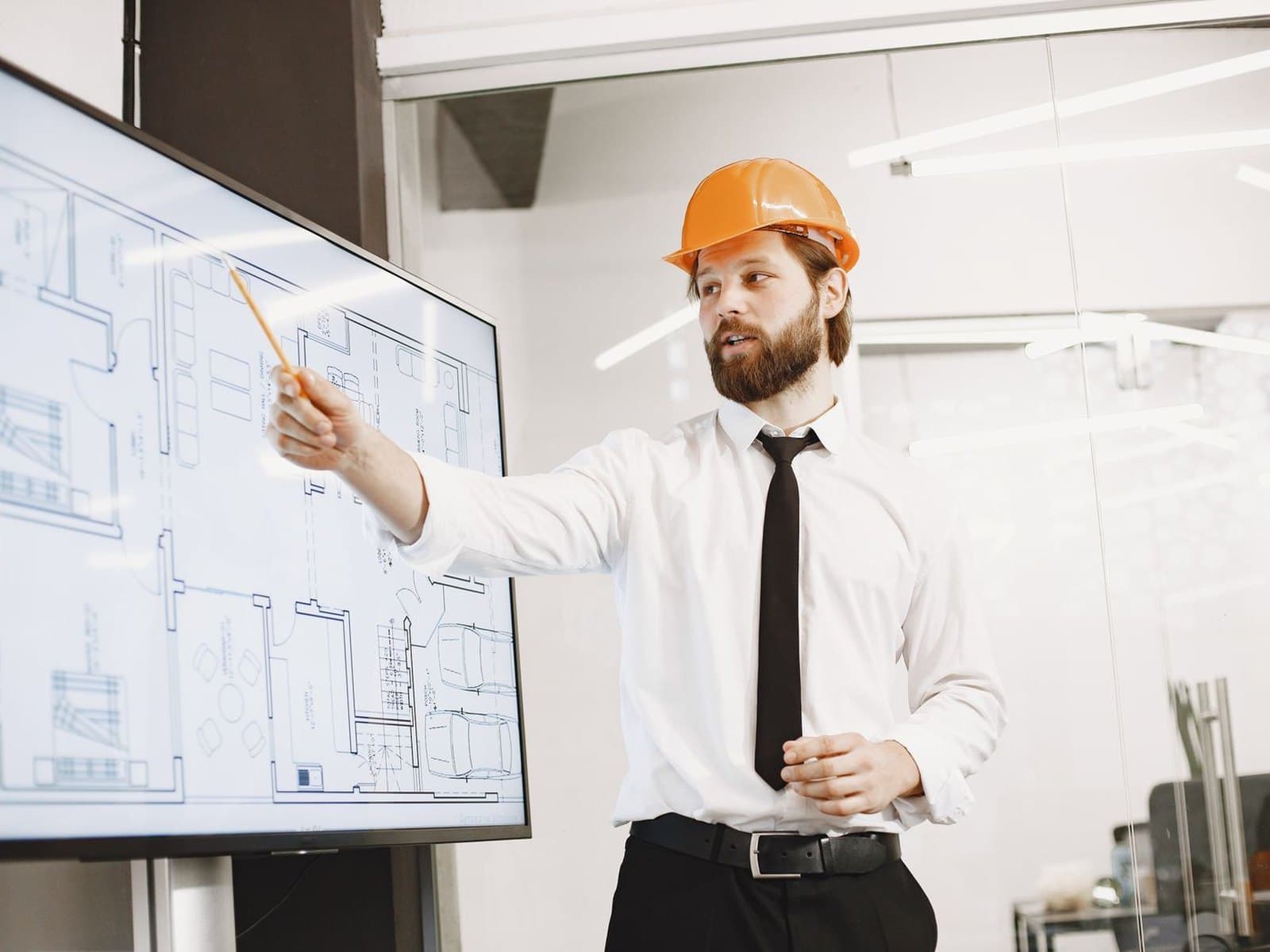 Un professionnel du bâtiment présente un plan sur un écran